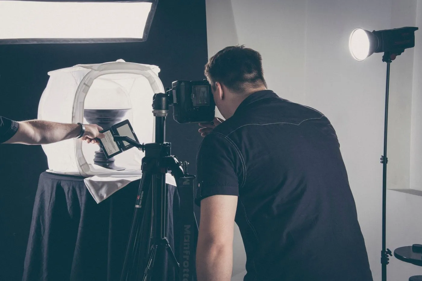 A photographer in a studio working with lighting gear and a camera
