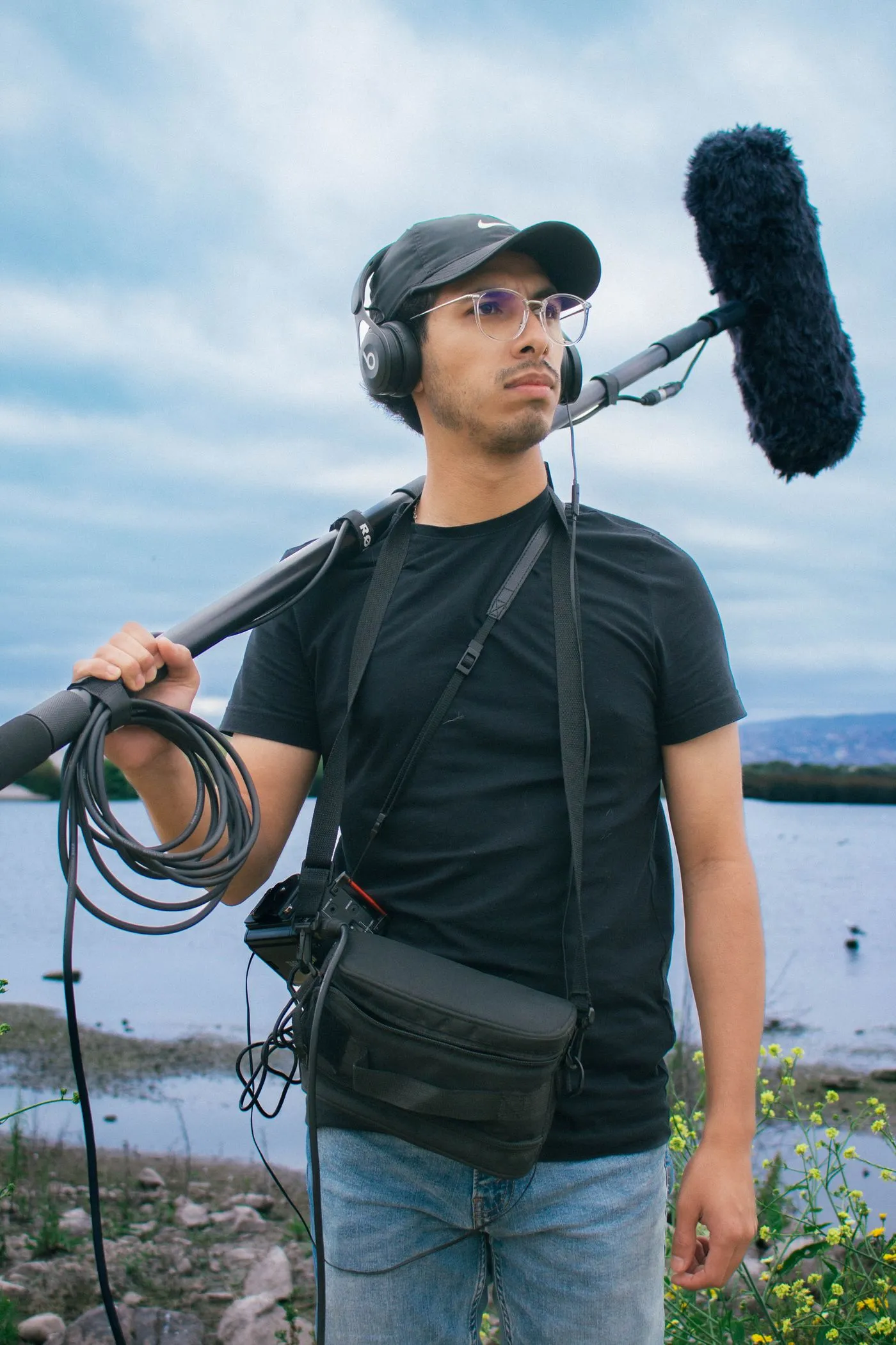 A boom operator in a headset holding a microphone pole outdoors