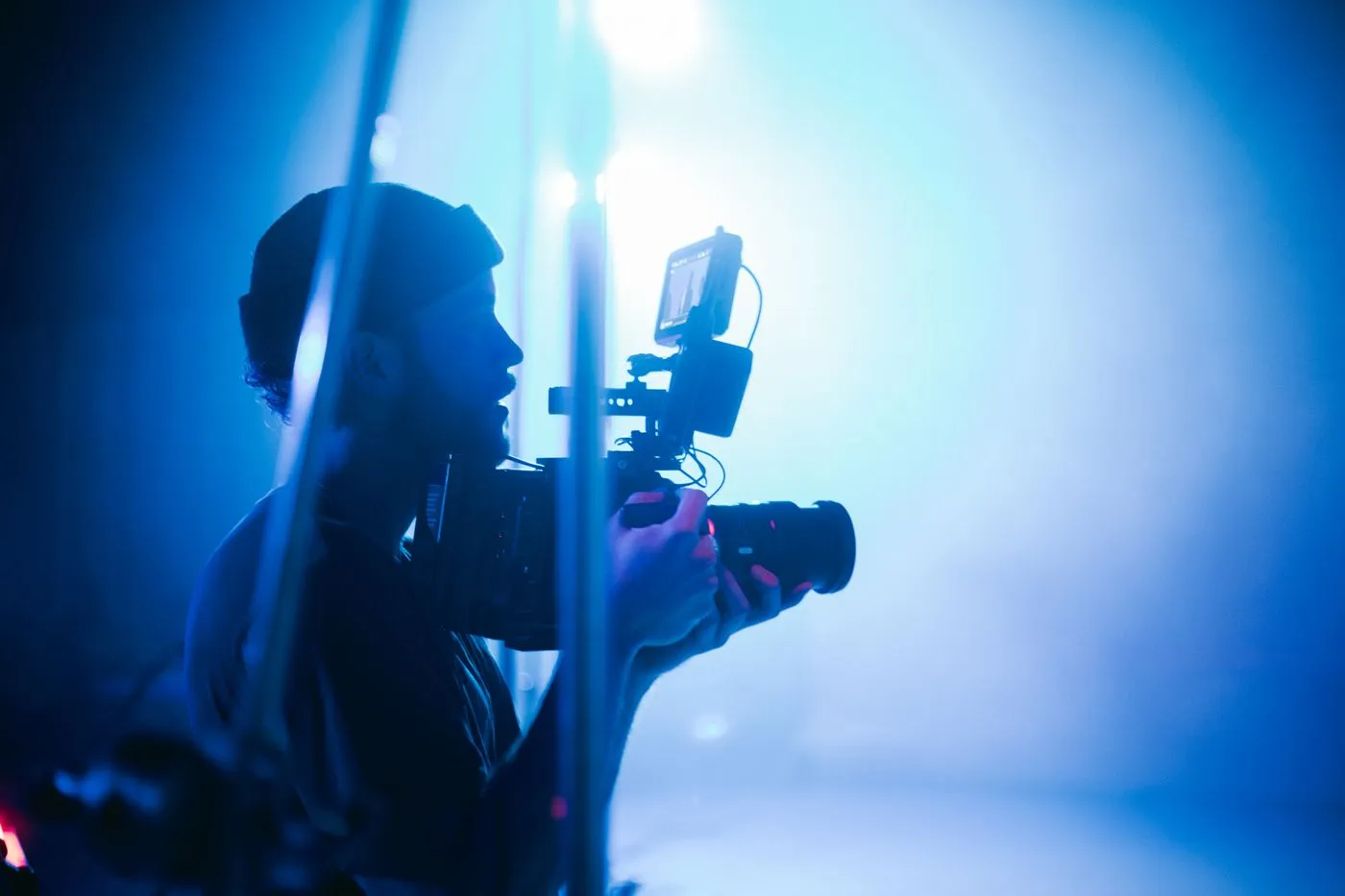 A cinematographer silhouetted in blue light holding a camera