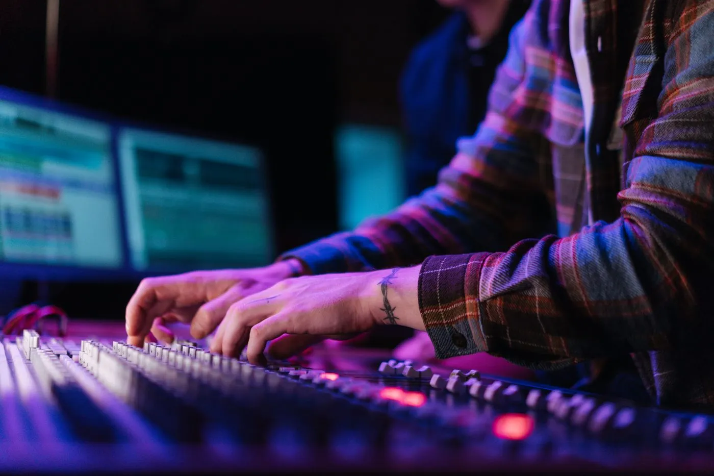 Hands adjusting an audio mixer in a dimly lit studio
