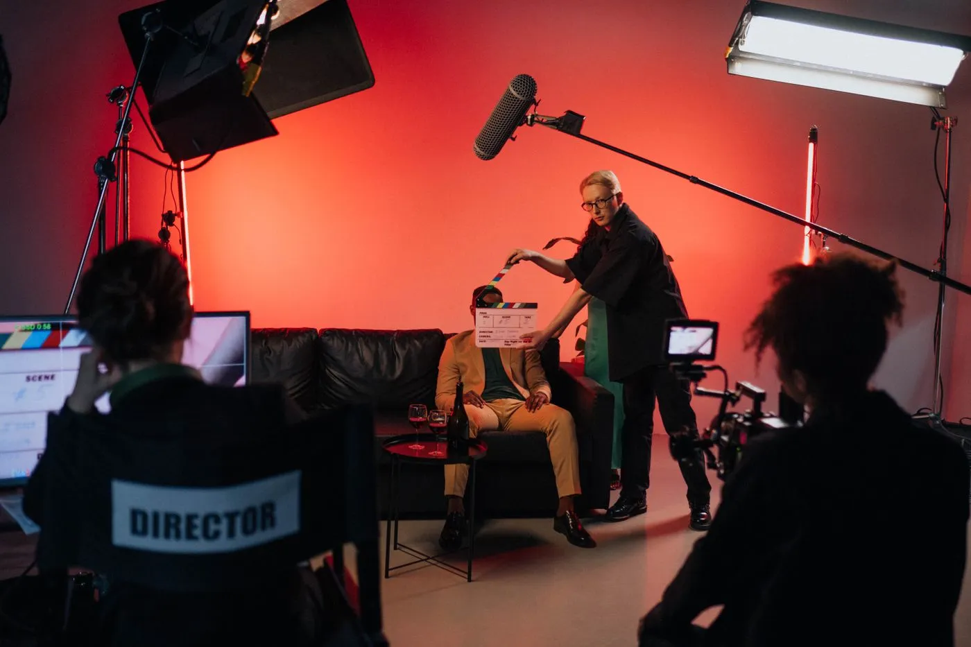 A film crew on set with a boom operator, lights and a director's chair